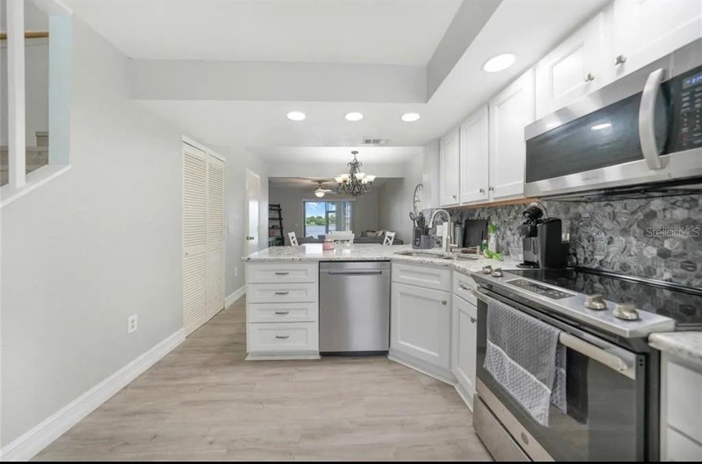 26272 Rampart Boulevard, Unit 107 Punta Gorda, FL 33983 - Photo 5 of 18 a kitchen with white cabinets stainless steel appliances and sink