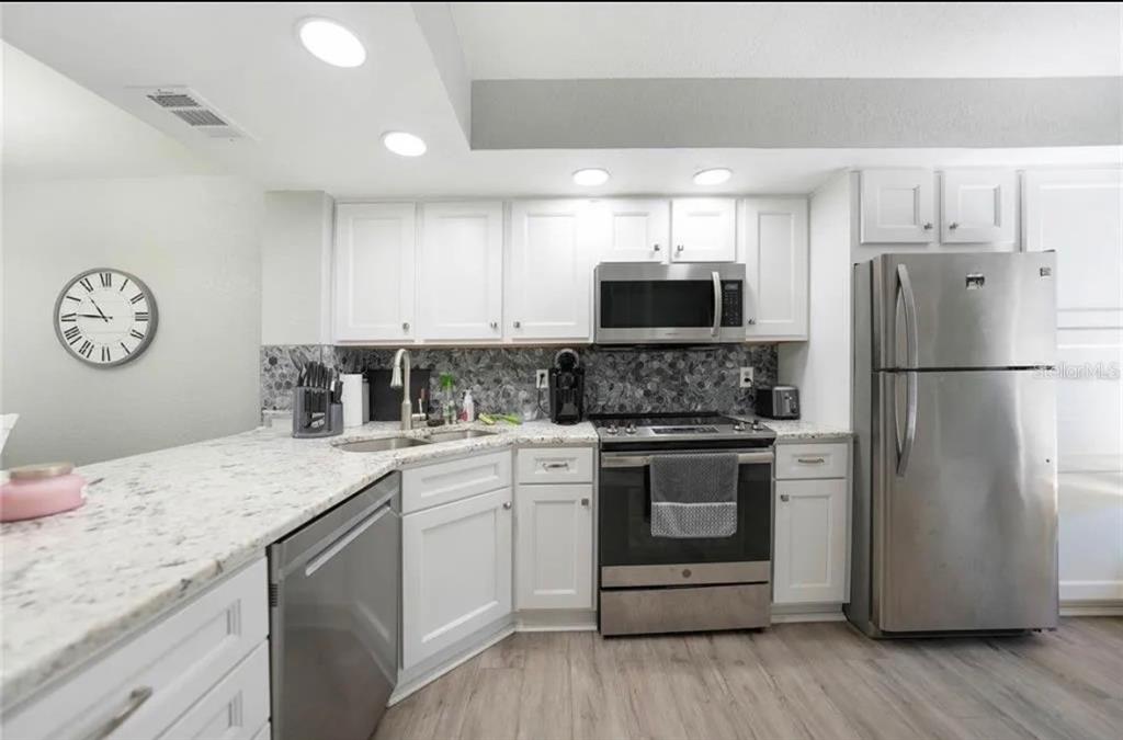 26272 Rampart Boulevard, Unit 107 Punta Gorda, FL 33983 - Photo 6 of 18 a kitchen with a refrigerator sink and cabinets