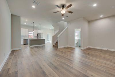 721 North Jefferson Street Pilot Point, TX 76258 - Photo 2 of 12 an empty room with wooden floor ceiling fan and kitchen view