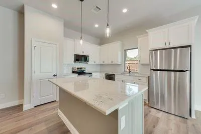 a kitchen with stainless steel appliances granite countertop a refrigerator a sink dishwasher a stove and a refrigerator with wooden floor