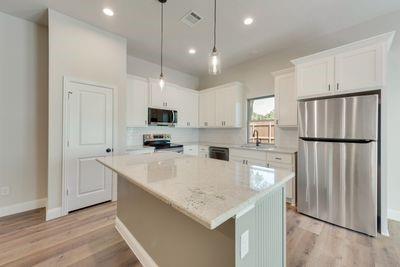 721 North Jefferson Street Pilot Point, TX 76258 - Photo 3 of 12 a kitchen with stainless steel appliances granite countertop a refrigerator a sink dishwasher a stove and a refrigerator with wooden floor