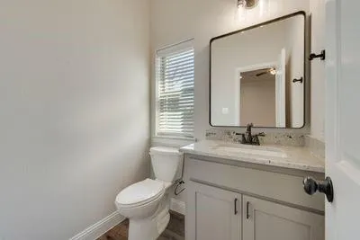 a bathroom with a granite countertop toilet sink and mirror