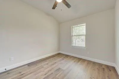 an empty room with a window and a ceiling fan