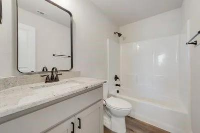a bathroom with a granite countertop sink a toilet and a large mirror