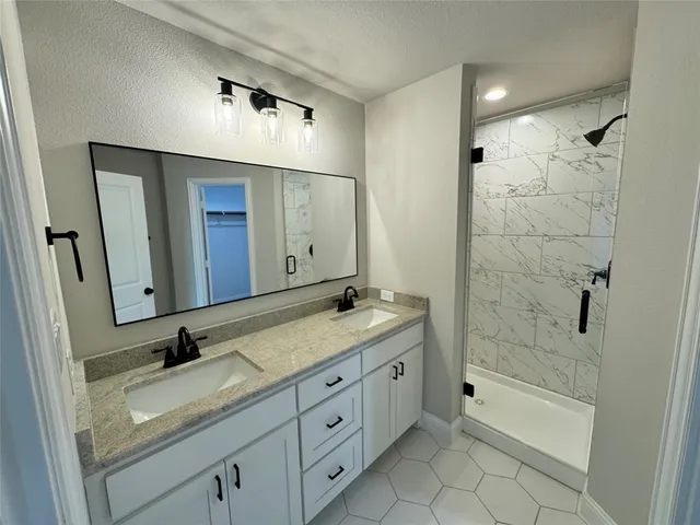 a bathroom with a granite countertop sink a mirror and a bathtub