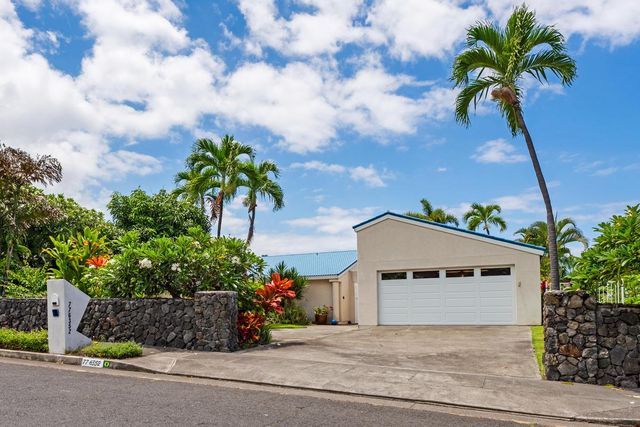 a front view of a house with a garden and trees