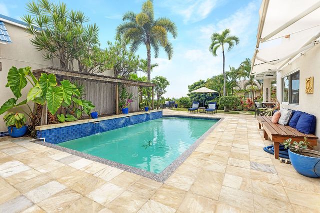 a swimming pool with outdoor seating and potted plants