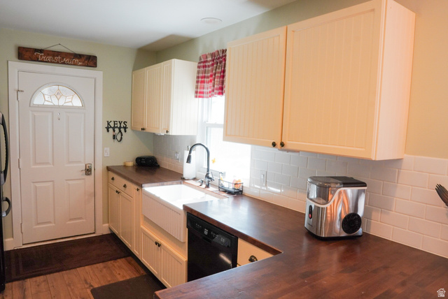 324 Stringtown Road Georgetown, ID 83239 - Photo 12 of 49 Kitchen with black dishwasher, decorative backsplash, dark wood-style floors, and freestanding refrigerator