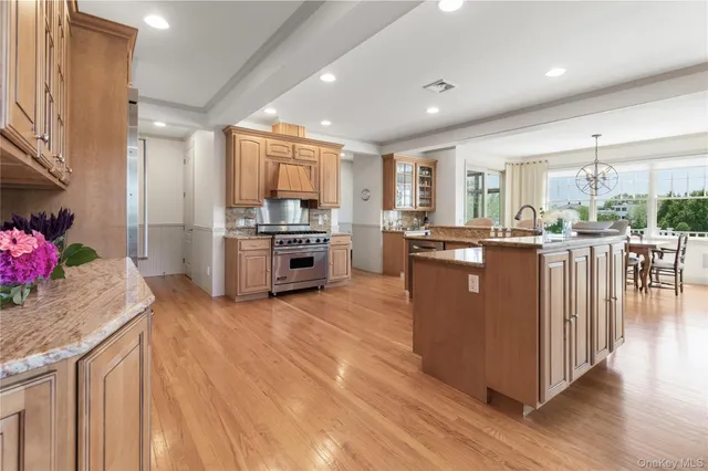 a kitchen with stainless steel appliances granite countertop a stove top oven a sink dishwasher and a refrigerator with wooden floor