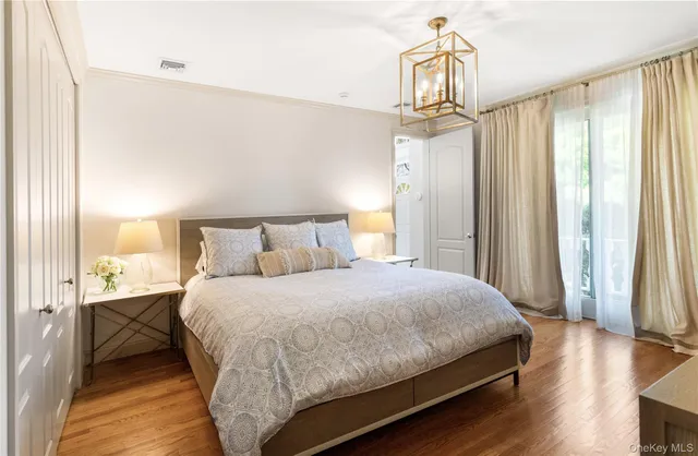 a bedroom with a bed a window and wooden floor