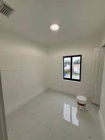 a view of a refrigerator in kitchen and an empty room