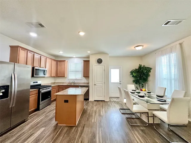 a kitchen with stainless steel appliances granite countertop a refrigerator a stove top oven a sink dishwasher and white cabinets with wooden floor