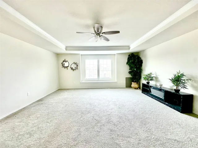 an empty room with windows and ceiling fan
