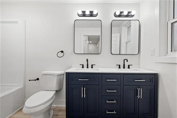 a bathroom with double vanity two toilet a sink and a mirror