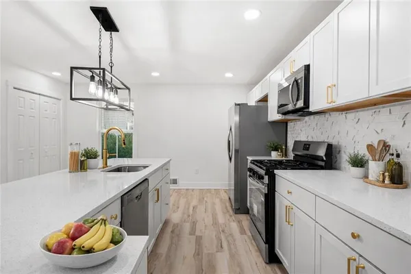 a kitchen with stainless steel appliances granite countertop a sink a stove and a wooden floors