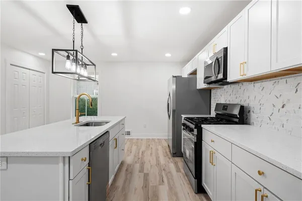 a kitchen with stainless steel appliances a sink a stove a refrigerator a center island and cabinets