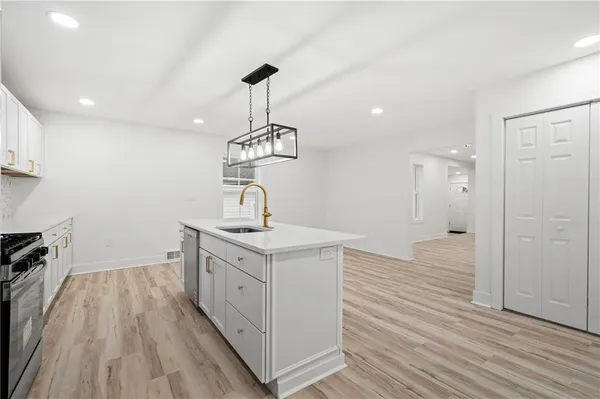 a kitchen with a sink stainless steel appliances and wooden floor