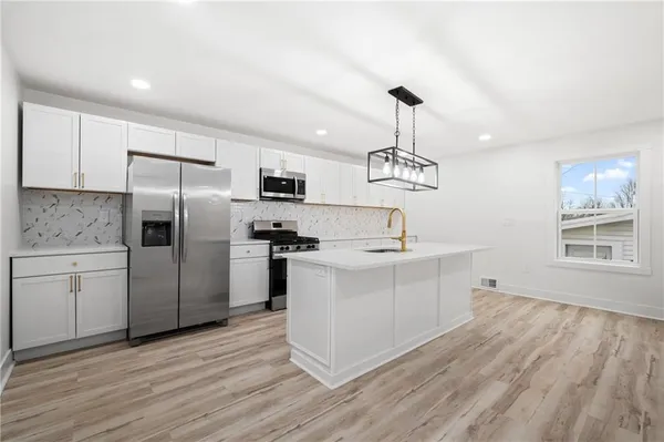a kitchen with a sink stainless steel appliances and wooden floor