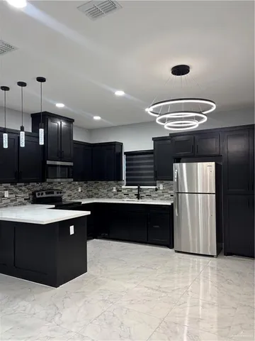 a kitchen with stainless steel appliances granite countertop a refrigerator a sink a stove and a refrigerator