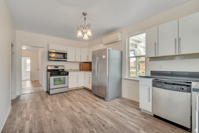 8831 South 400 East Sandy, UT 84070 - Photo 21 of 26 Kitchen featuring stainless steel appliances, white cabinetry, healthy amount of natural light, and a chandelier