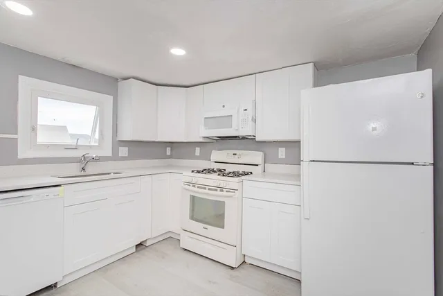 a kitchen with cabinets appliances a sink and a window