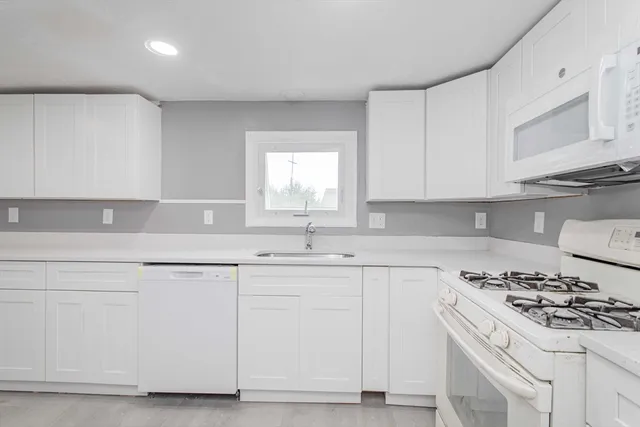 a kitchen with granite countertop white cabinets and white appliances