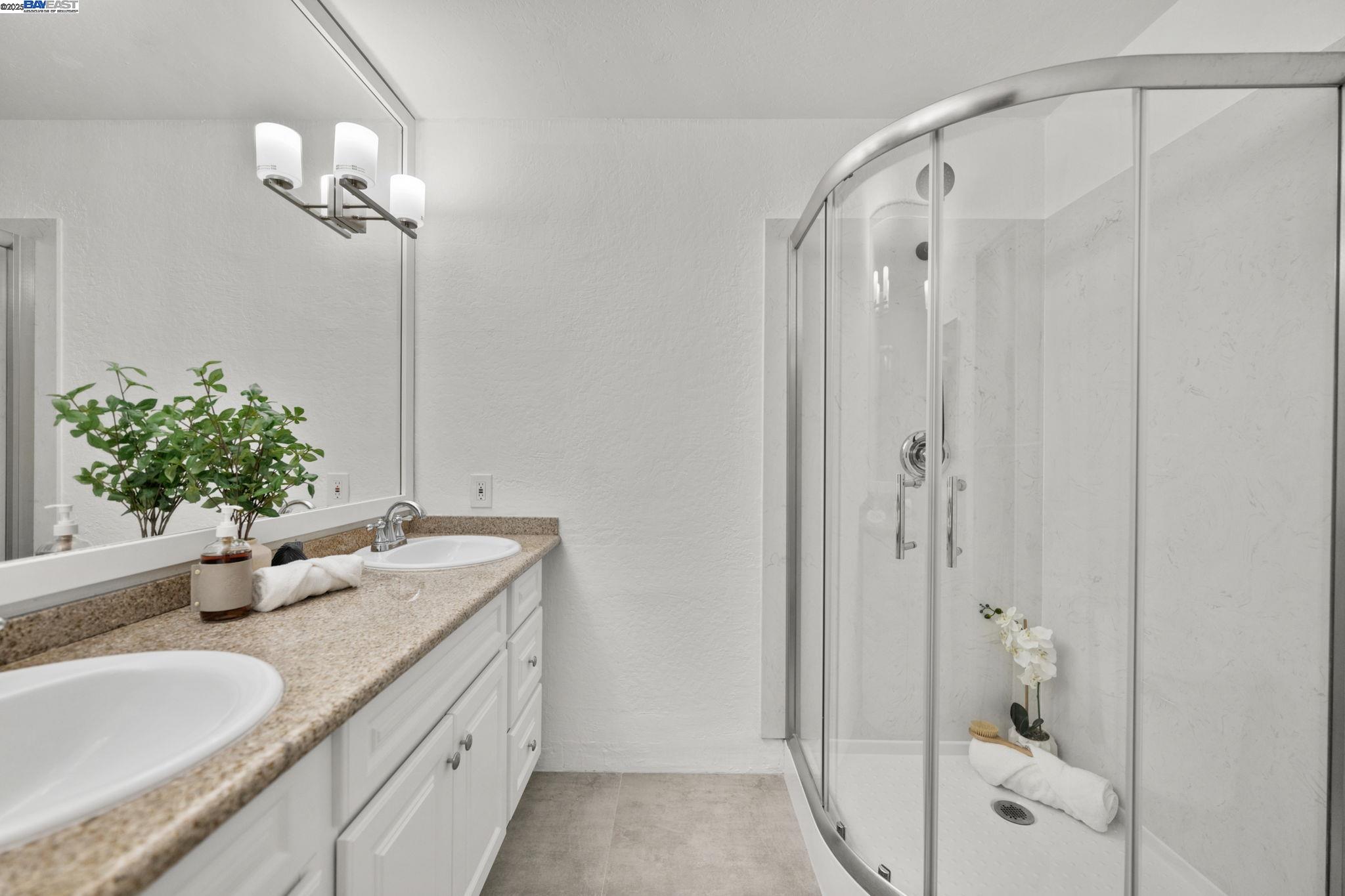 1085 Murrieta Boulevard, Unit 222 Livermore, CA 94550 - Photo 19 of 25 a bathroom with a granite countertop sink a mirror and a shower