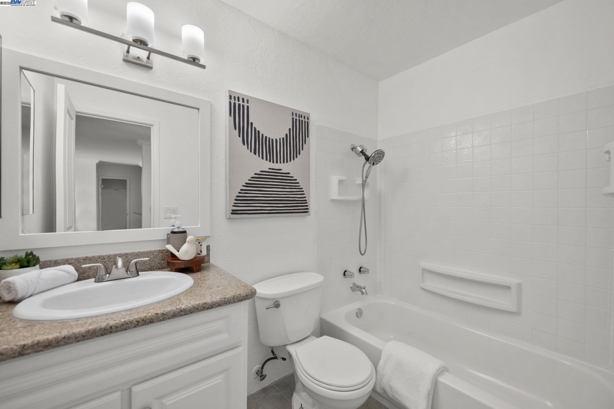 1085 Murrieta Boulevard, Unit 222 Livermore, CA 94550 - Photo 24 of 25 a bathroom with a granite countertop sink toilet a mirror and shower