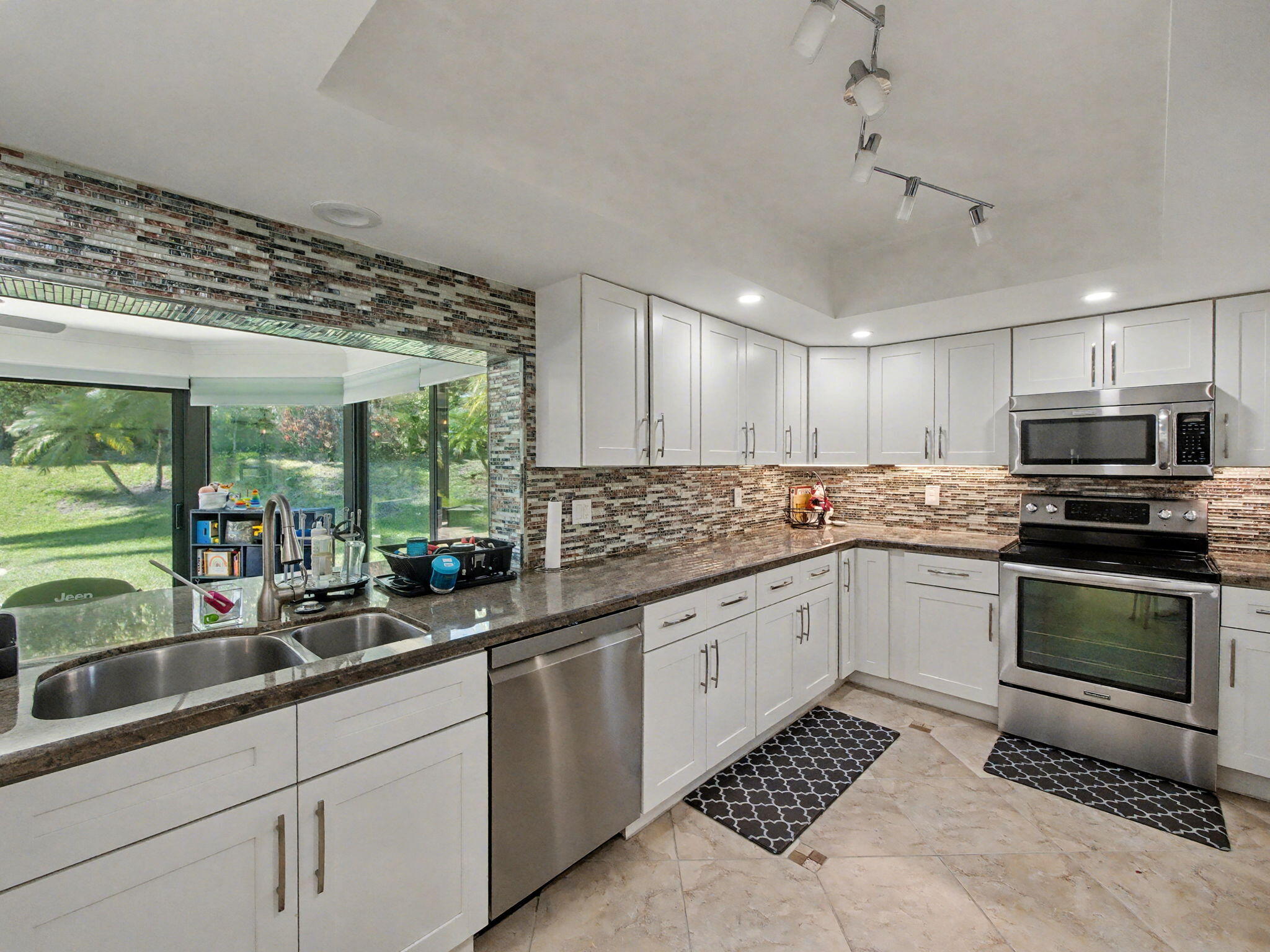 720 Muirfield Circle Atlantis, FL 33462 - Photo 18 of 20 a kitchen with a sink window and cabinets
