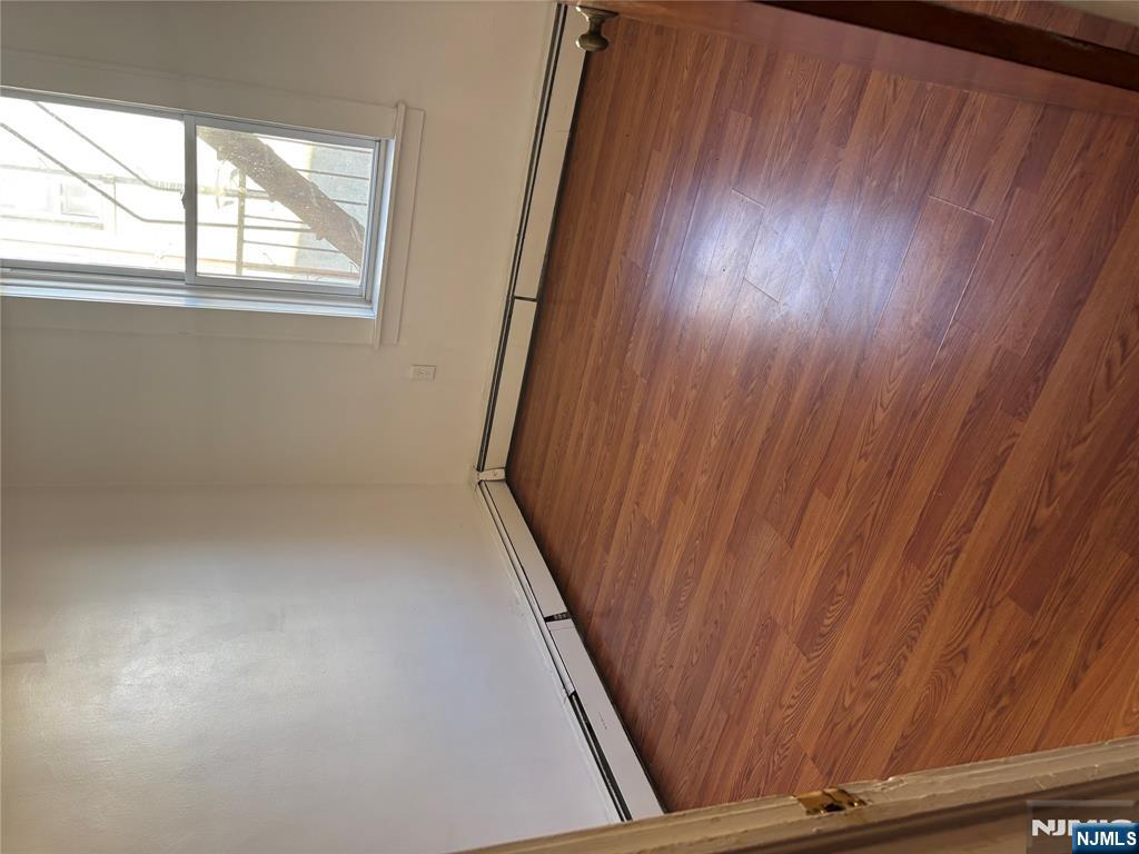 86 Center Street, Unit 2R Clifton, NJ 07011 - Photo 7 of 8 an empty room with wooden floor and windows