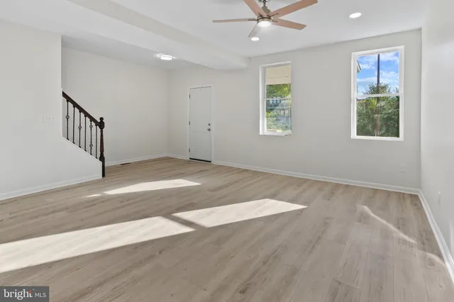 an empty room with wooden floor fan and windows