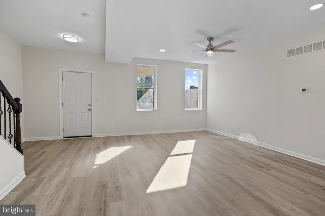 an empty room with wooden floor and windows