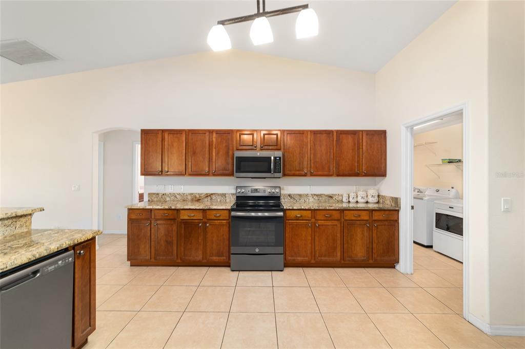 4037 Southeast 40th Street Ocala, FL 34480 - Photo 18 of 38 a large kitchen with granite countertop a stove top oven microwave and cabinets