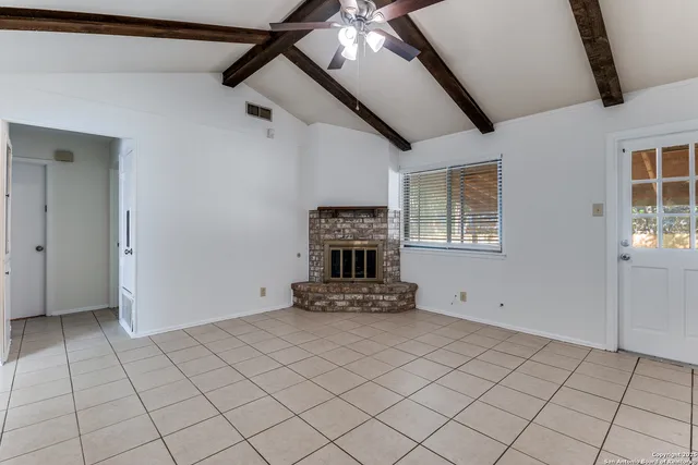 a view of an empty room with wooden floor and a fireplace