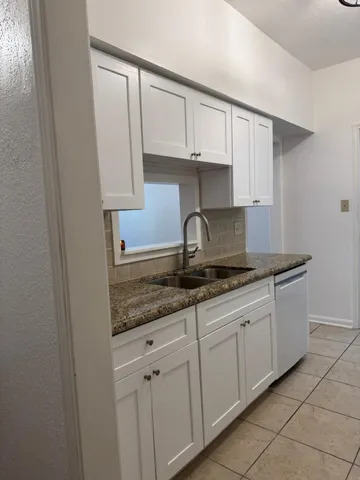a kitchen with granite countertop white cabinets and a sink
