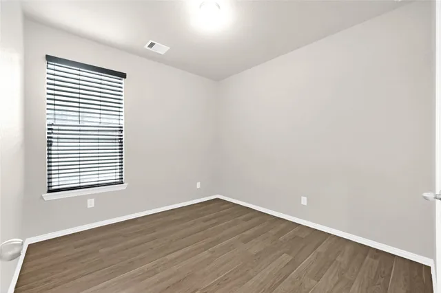 an empty room with wooden floor and a window