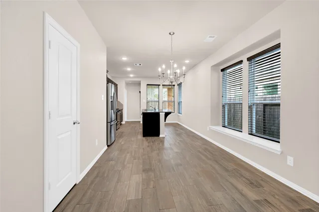 a view of a big room with wooden floor kitchen and windows