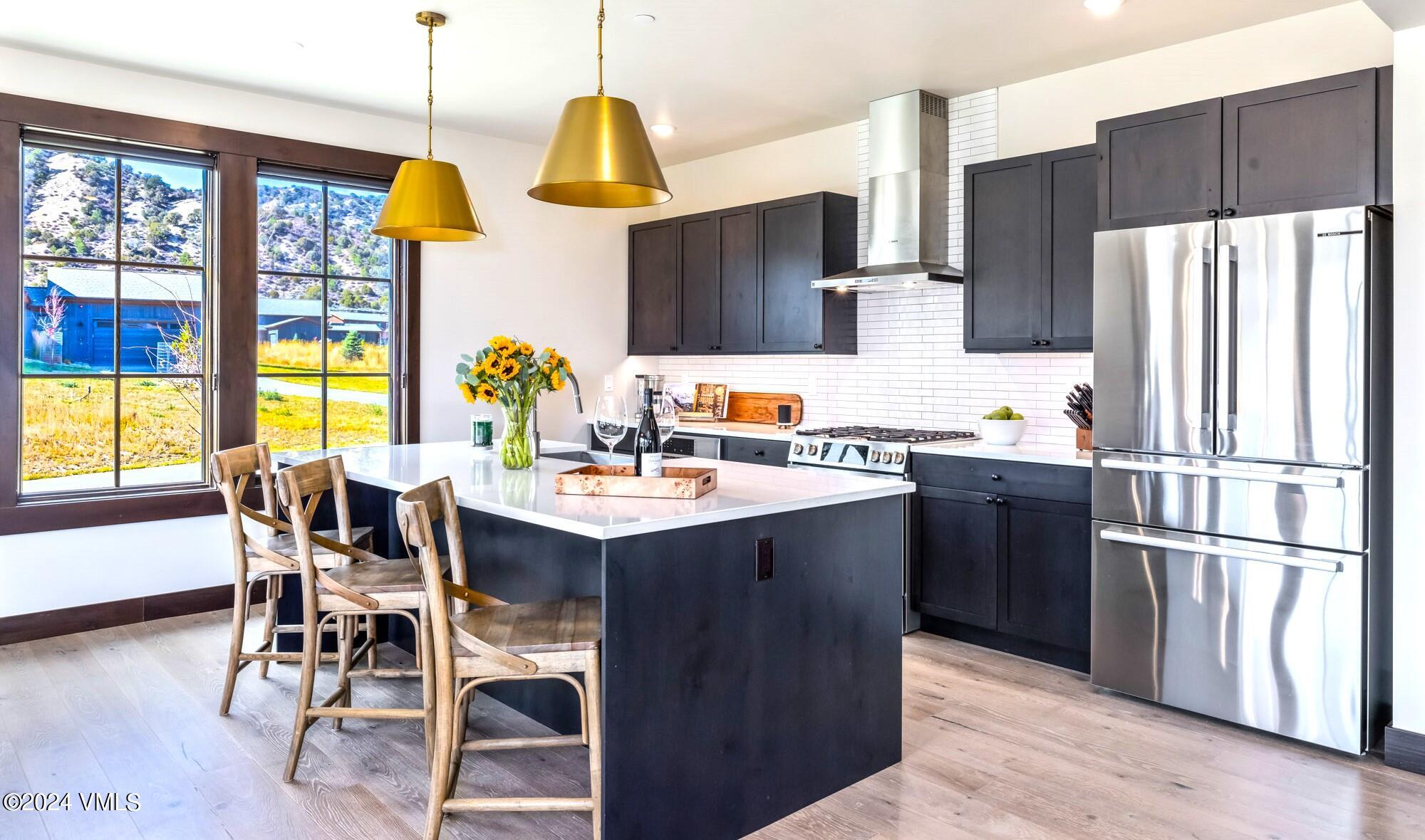 448 Hunters View Lane Eagle, CO 81631 - Photo 15 of 35 a kitchen with stainless steel appliances a dining table chairs refrigerator and sink