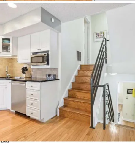 a kitchen with wooden floors white cabinets and stainless steel appliances