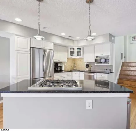 a kitchen with stainless steel appliances granite countertop a sink a refrigerator and a granite counter tops