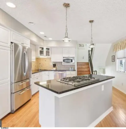 a kitchen with stainless steel appliances granite countertop a sink a stove and a refrigerator