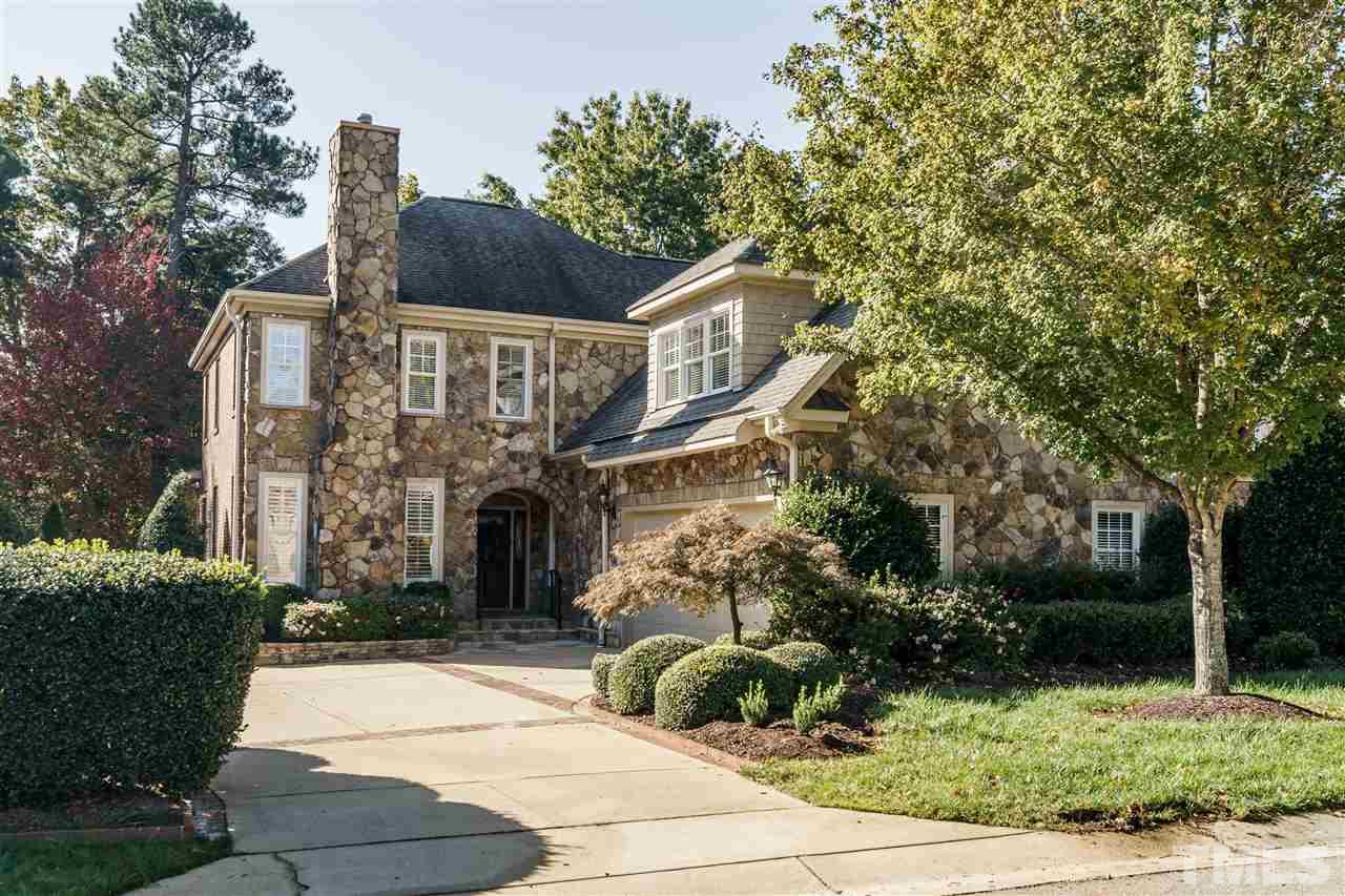 a view of a house with brick walls plants and large tree