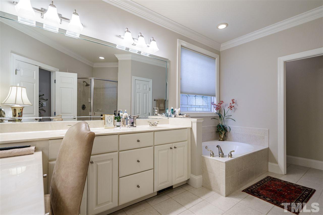 1901 Torrington Street Raleigh, NC 27615 - Photo 18 of 30 a bathroom with a bathtub a double vanity sink and a mirror