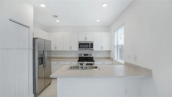 a kitchen with a refrigerator a stove and a sink with wooden floor