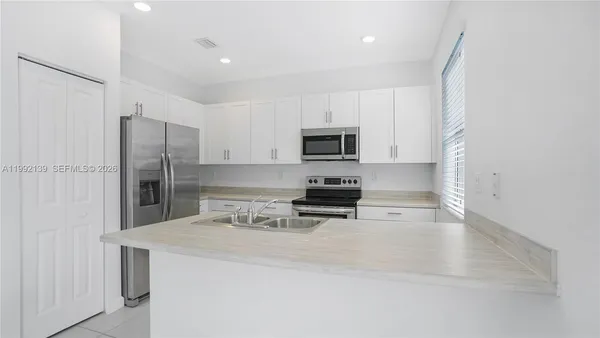 a kitchen with a sink a microwave a refrigerator and cabinets