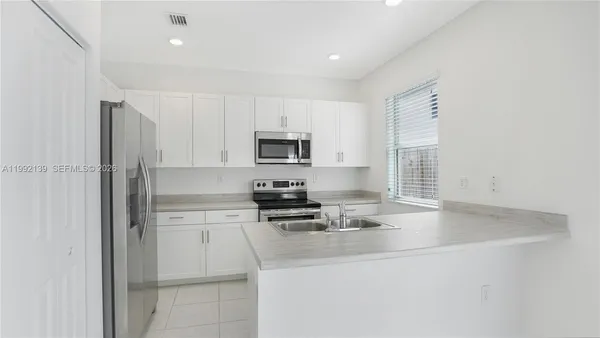 a kitchen with appliances a sink and cabinets