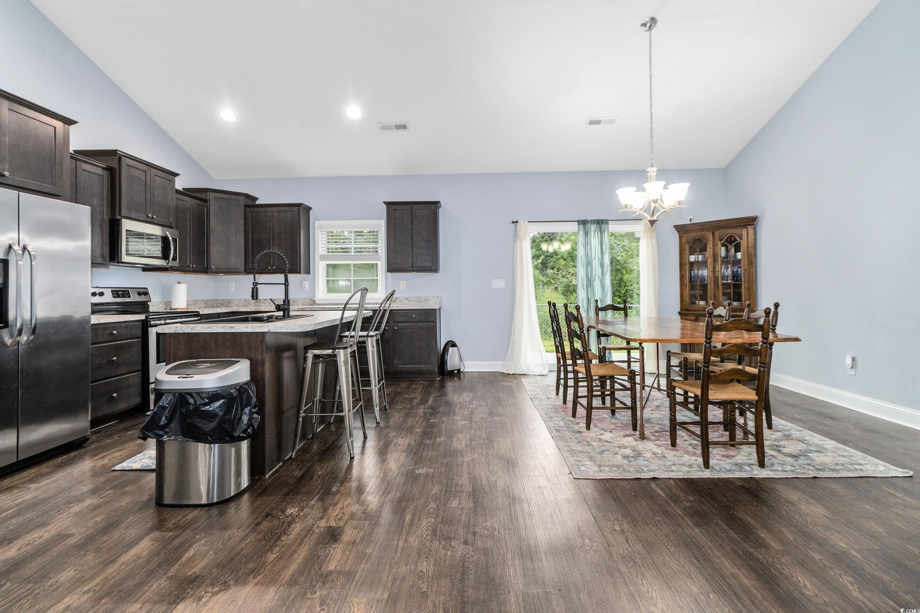 4867 Wolf Trail Conway, SC 29527 - Photo 13 of 31 Kitchen featuring a breakfast bar area, dark brown cabinets, appliances with stainless steel finishes, a kitchen island with sink, and dark wood-type flooring