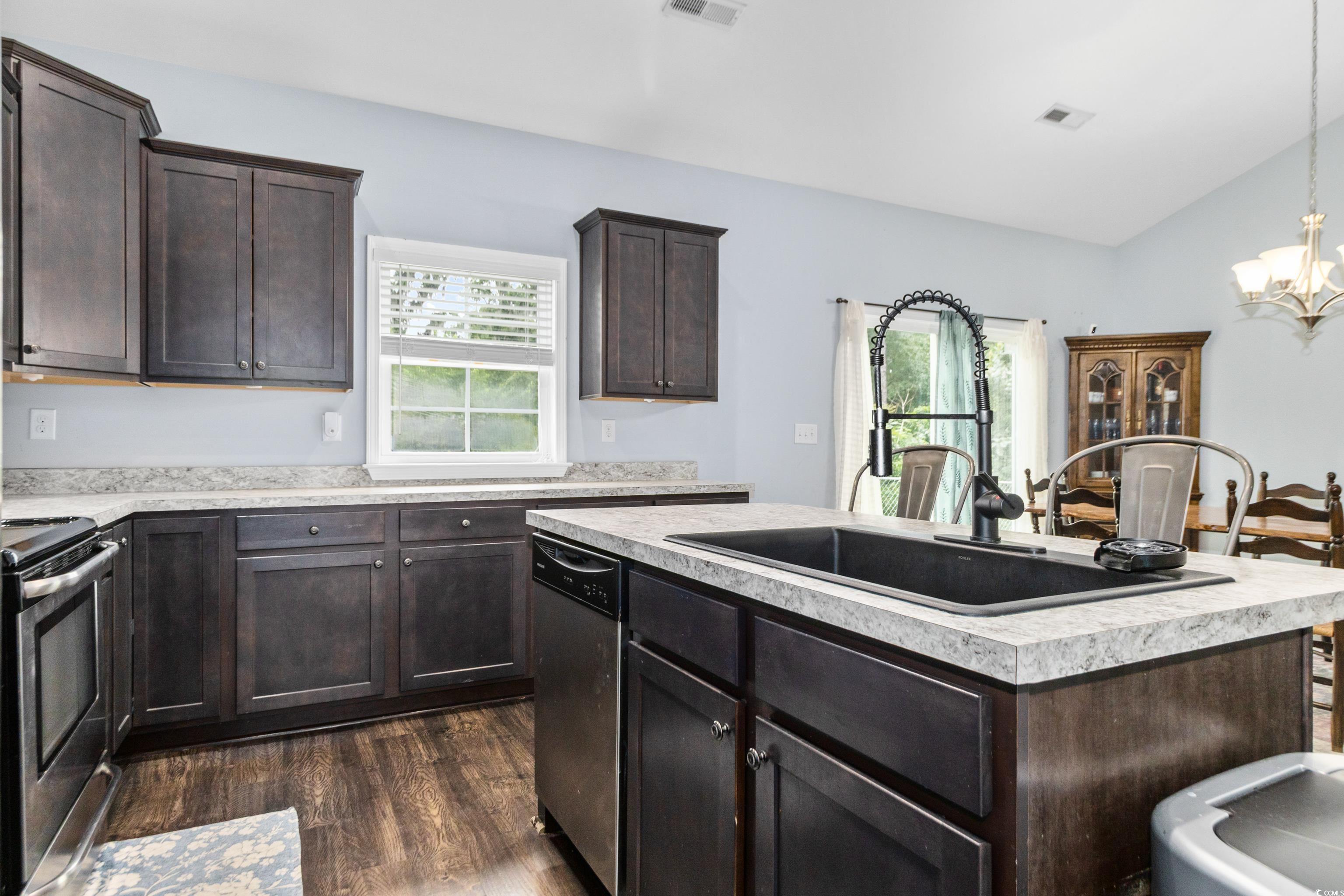 4867 Wolf Trail Conway, SC 29527 - Photo 14 of 31 Kitchen with dark brown cabinets, light countertops, healthy amount of natural light, dark wood-style floors, and lofted ceiling