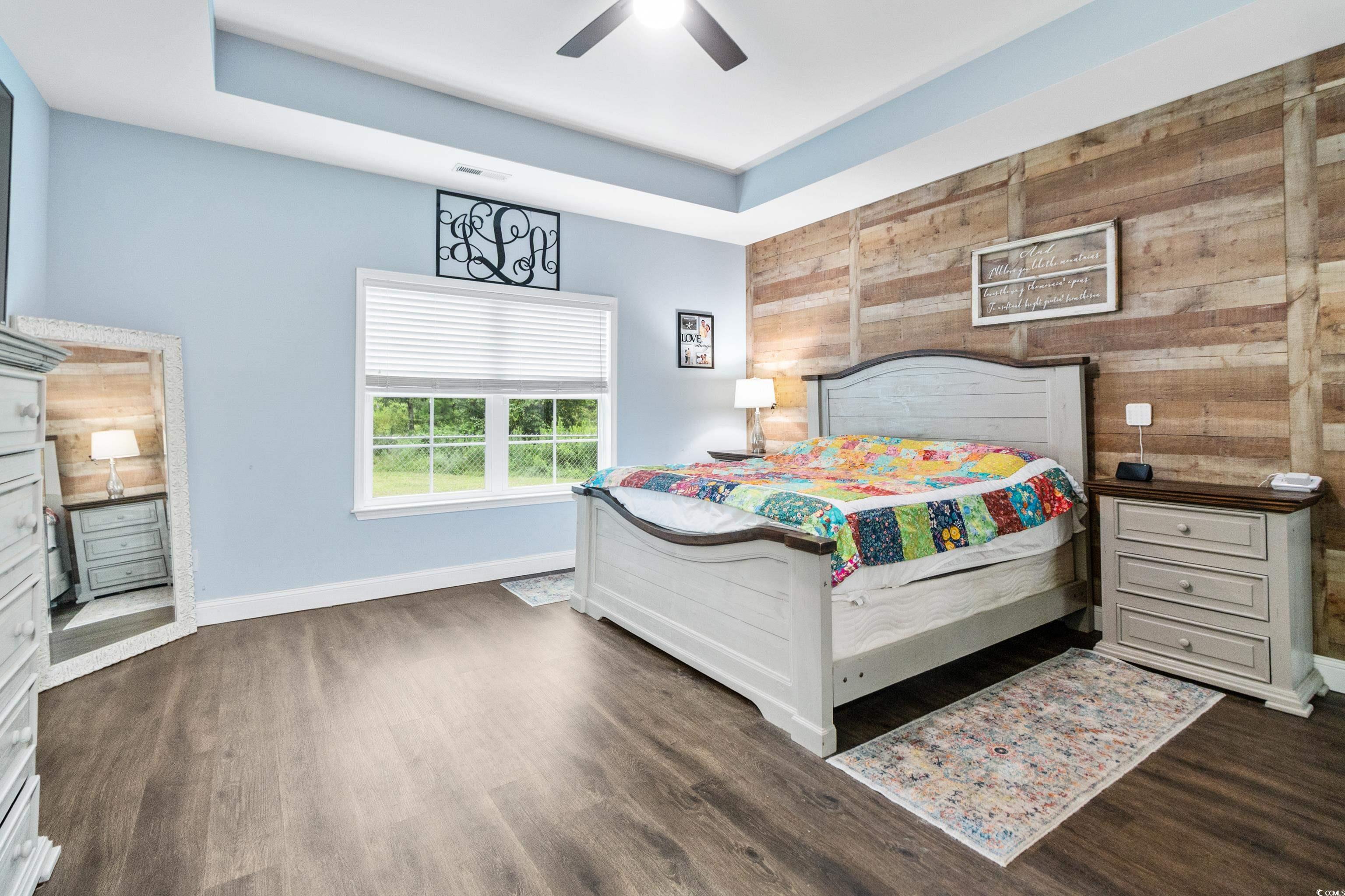 4867 Wolf Trail Conway, SC 29527 - Photo 15 of 31 Bedroom featuring wooden walls, dark wood finished floors, a ceiling fan, and a raised ceiling