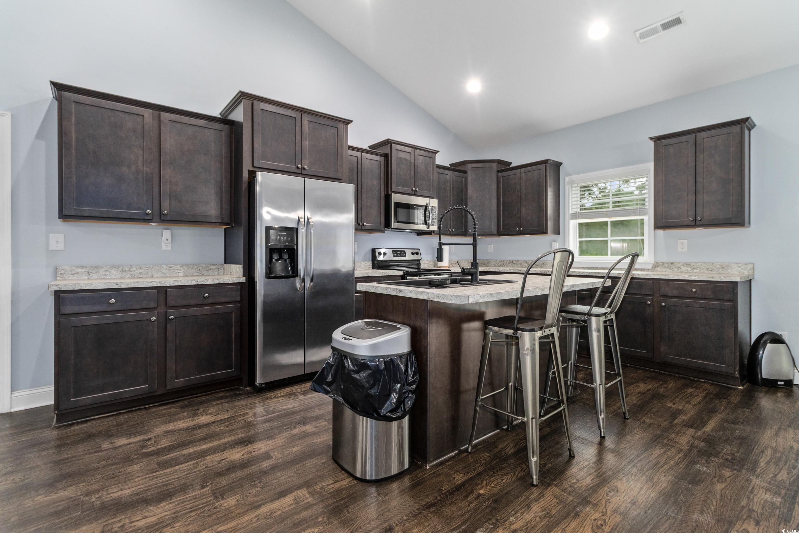 4867 Wolf Trail Conway, SC 29527 - Photo 10 of 31 Kitchen featuring dark brown cabinetry, appliances with stainless steel finishes, dark wood finished floors, a breakfast bar area, and a kitchen island with sink